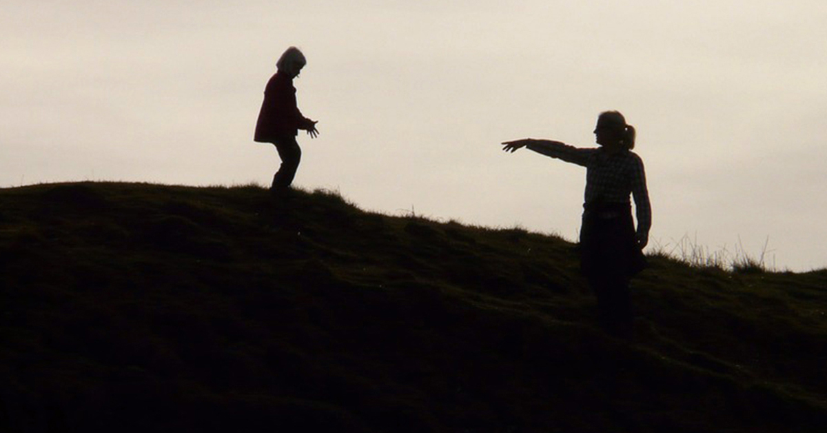 silhouette of an adult reaching for a child