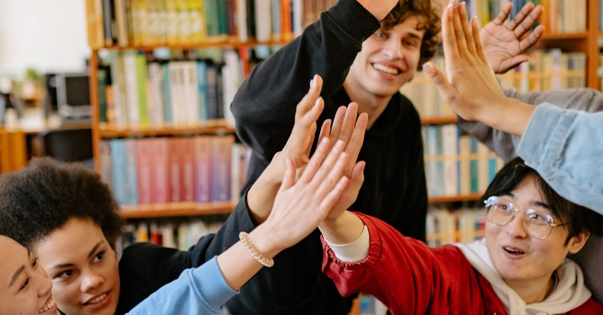 Photo of a diverse group of youth high-fiving each other.
