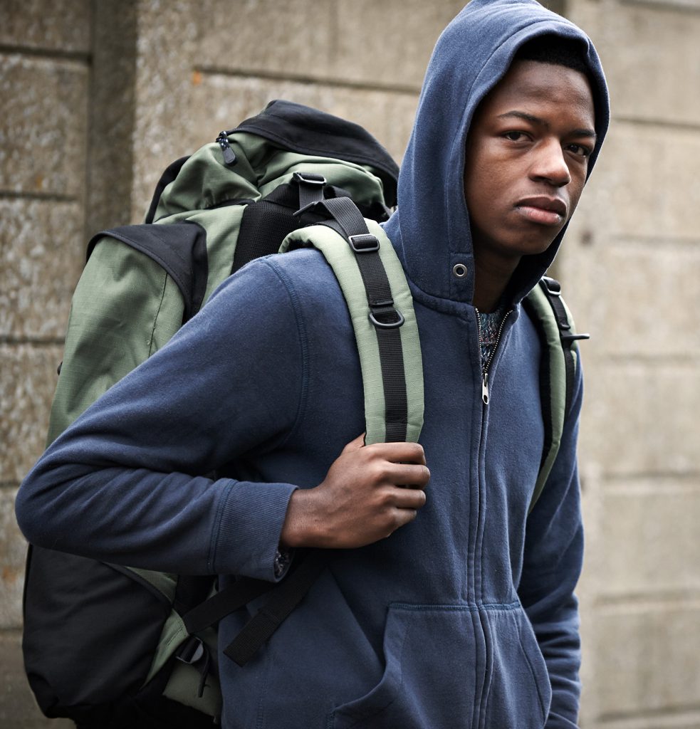 Photo of teen boy wearing a blue hoodie and carrying a backpack.