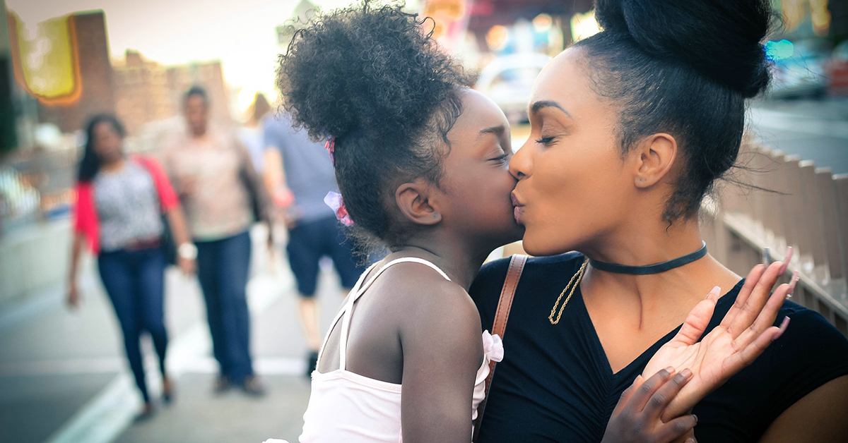 Mother giving her daughter a kiss.
